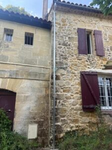 Descente d’eau pluviale en zinc posée sur une maison en pierre au Tourne